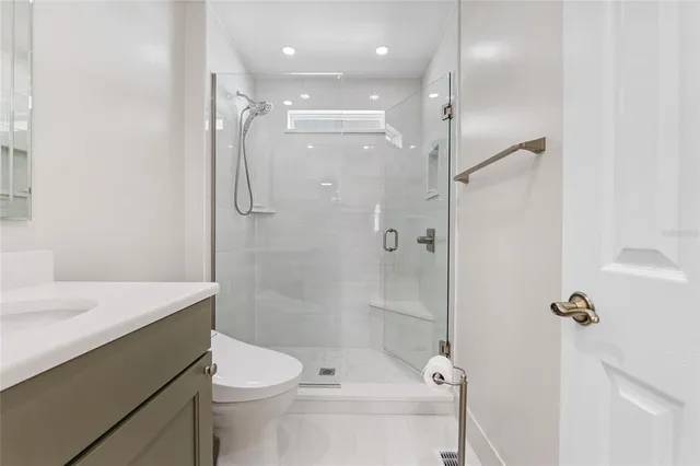 a bathroom with a shower sink vanity mirror and toilet