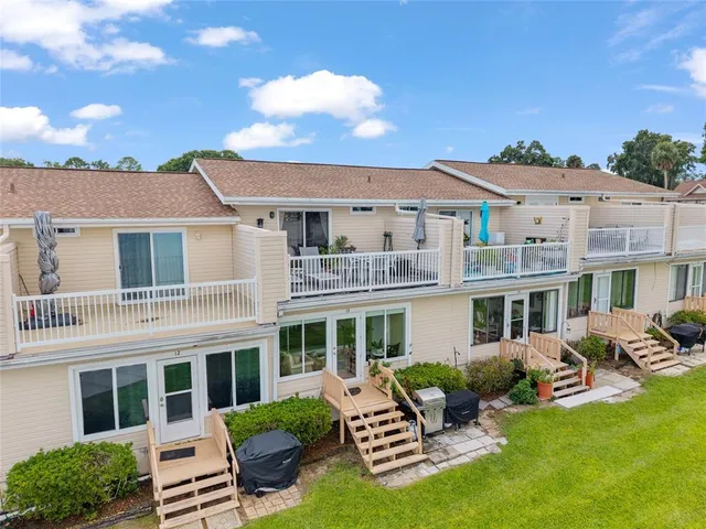 a view of a patio with couches chairs potted plants and large tree