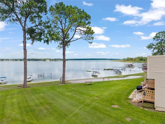 a view of a lake with a big yard and large trees