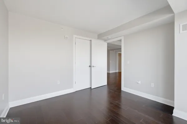 a view of an empty room with wooden floor and closet