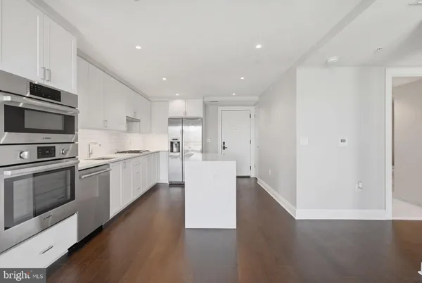 a kitchen with a refrigerator and white cabinets