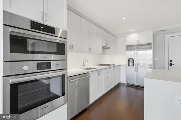 a kitchen with stainless steel appliances white cabinets and a stove top oven