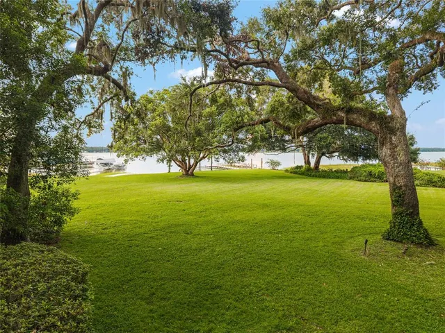 a view of a house with a big yard and large trees