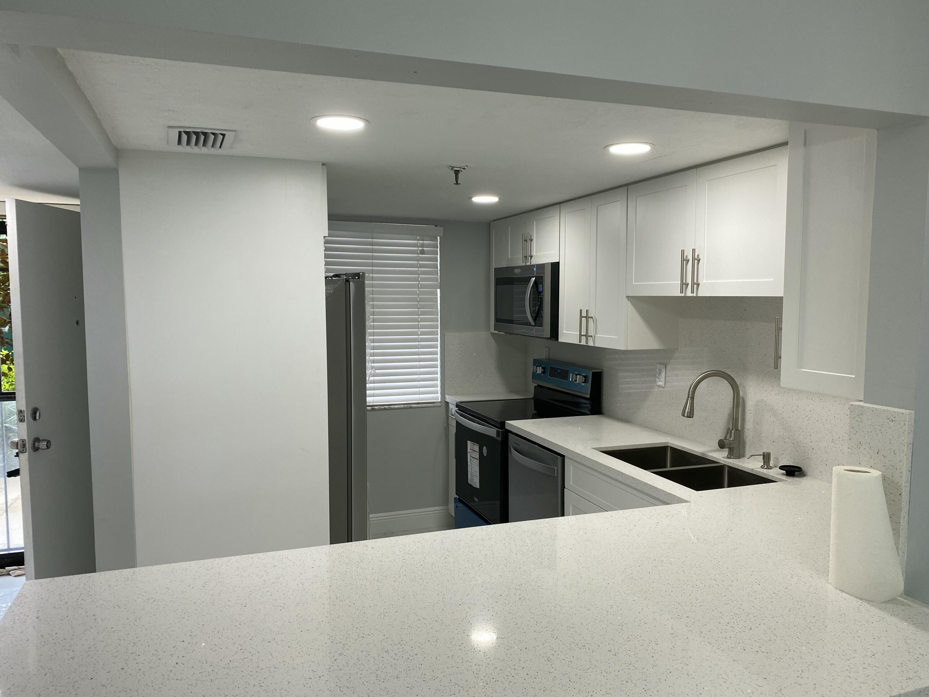 2788 Tennis Club Drive, Unit 102 West Palm Beach, FL 33417 - Photo 4 of 26 a kitchen with kitchen island a sink stainless steel appliances and cabinets