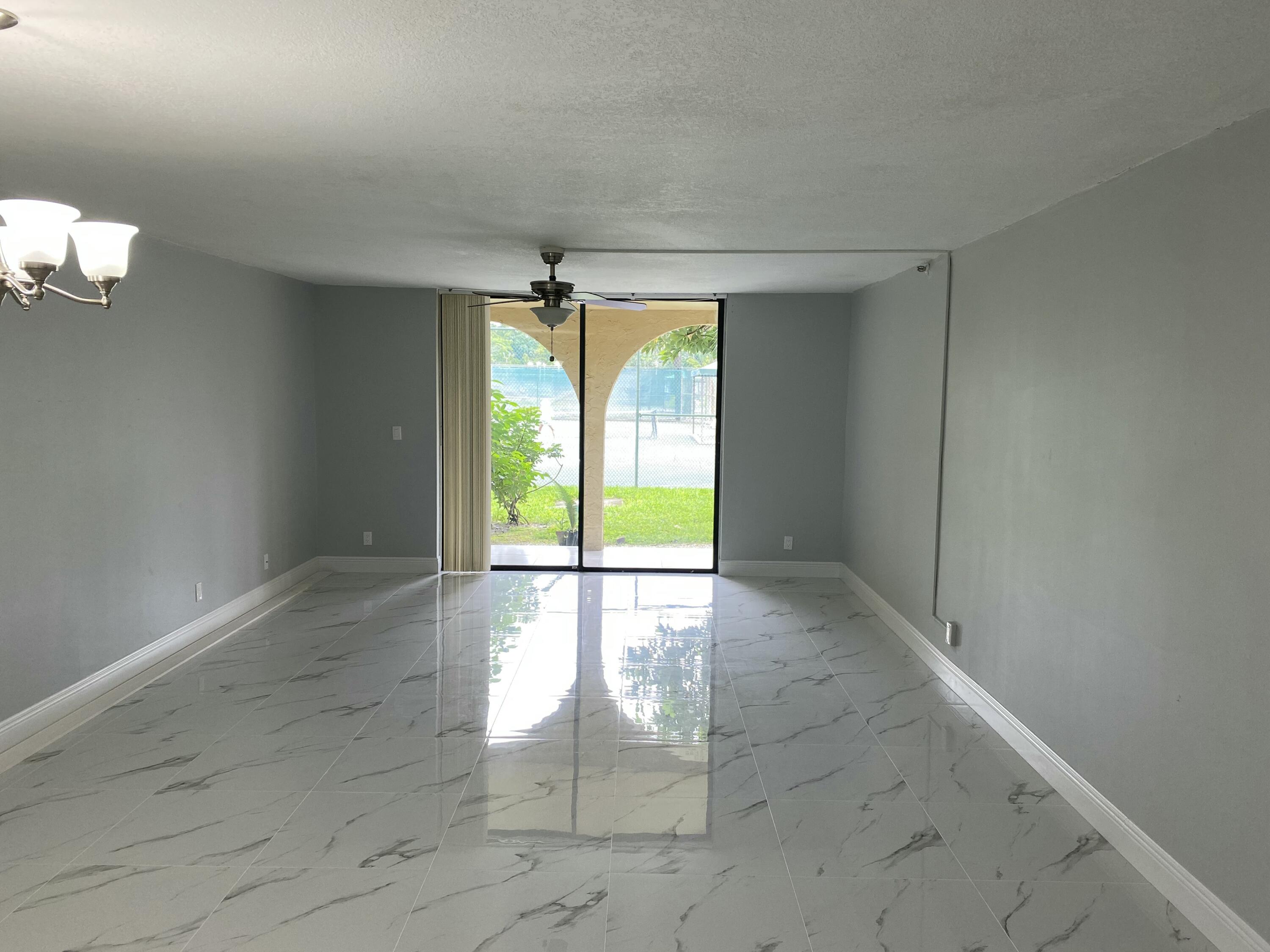 2788 Tennis Club Drive, Unit 102 West Palm Beach, FL 33417 - Photo 8 of 26 an empty room with windows and chandelier