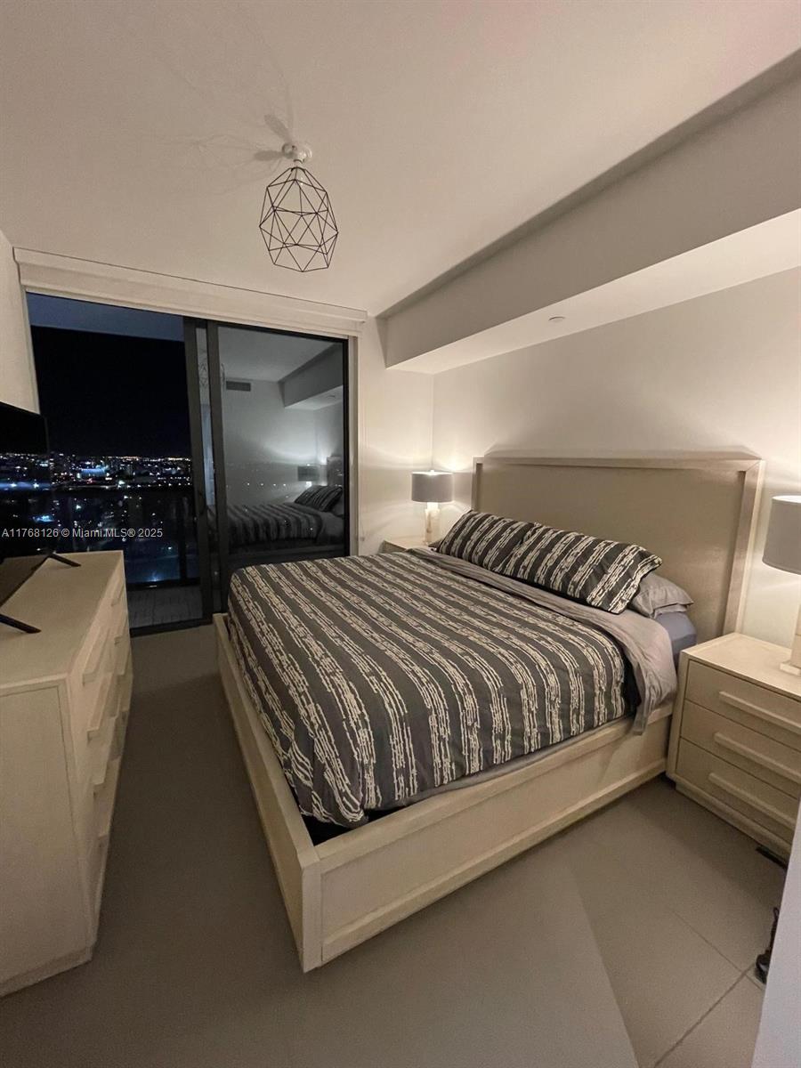 Omni Miami, FL 33132 - Photo 8 of 11 a spacious bedroom with a bed a couch and a flat screen tv