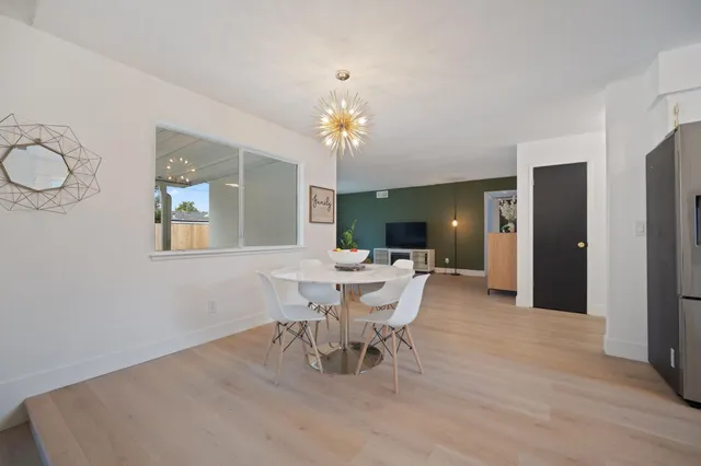 a dining room with wooden floor a chandelier a wooden table and chairs