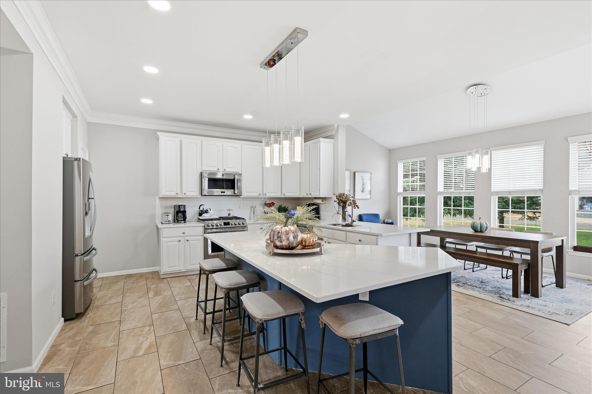 6711 Selbourne Lane Gainesville, VA 20155 - Photo 12 of 55 a kitchen with stainless steel appliances granite countertop a stove a refrigerator a sink a dining table and chairs with wooden floor