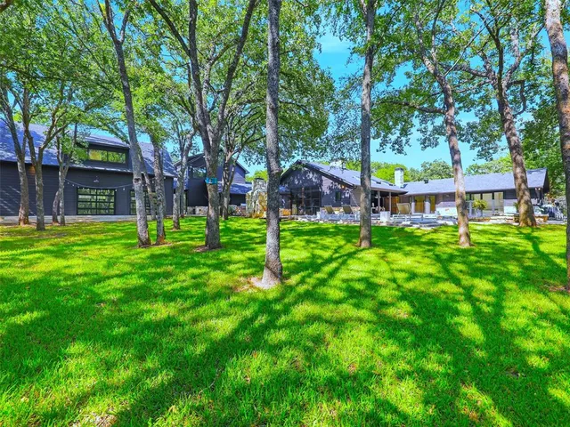 a view of white house with a big yard and large trees