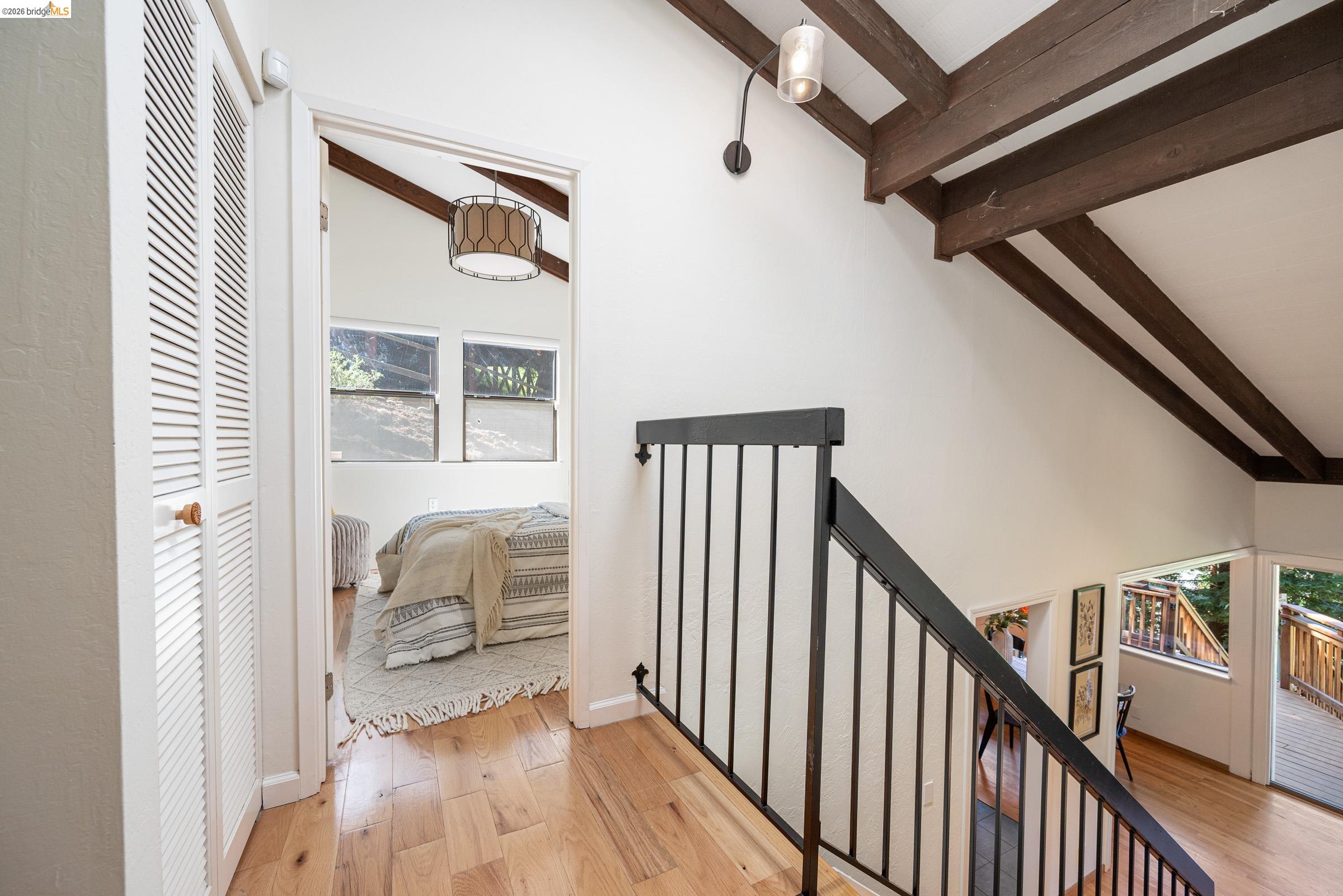 6600 Heather Ridge Way Oakland, CA 94611 - Photo 36 of 66 Upper-level hallway featuring wood-finish flooring, exposed wood ceiling beams, and a black metal railing