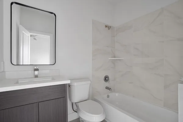 a bathroom with a bathtub shower sink vanity mirror and toilet