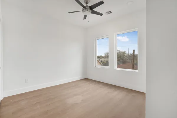 an empty room with a window and a ceiling fan