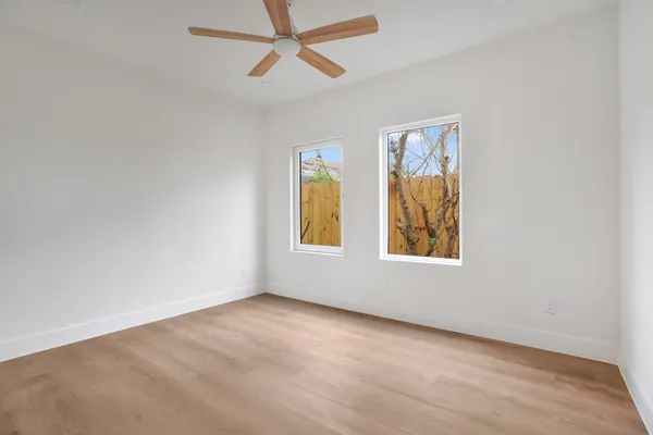 an empty room with windows and fan