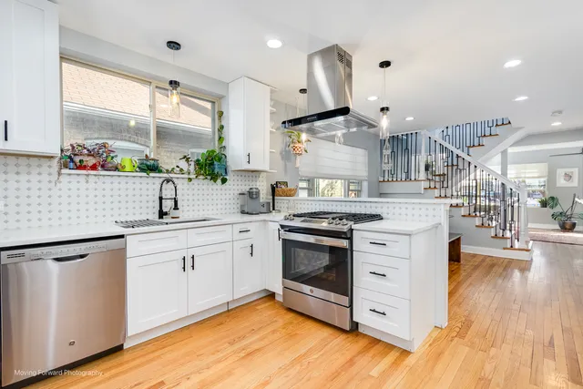 a kitchen with stainless steel appliances granite countertop a sink a stove and a wooden floors