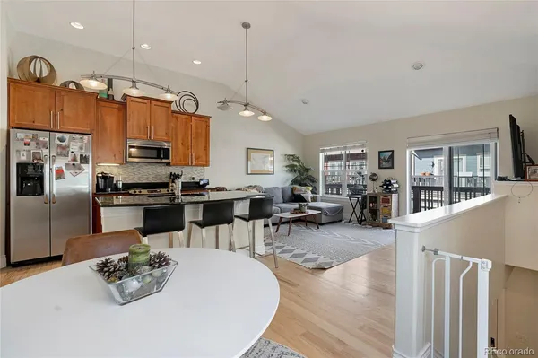 a kitchen with stainless steel appliances granite countertop a stove refrigerator and chairs with wooden floor