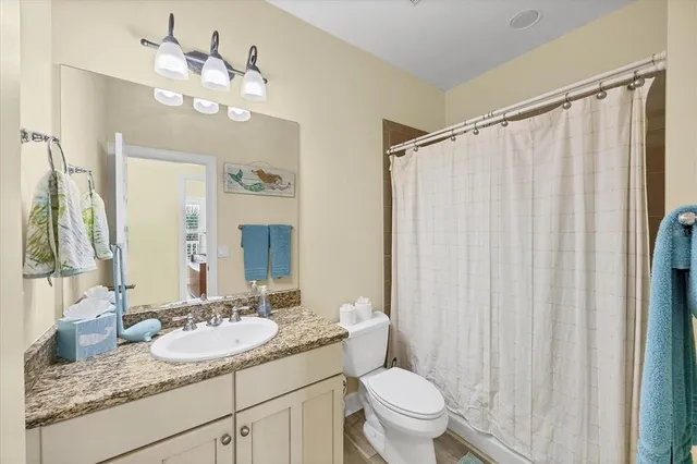 a bathroom with a granite countertop sink a toilet and a mirror