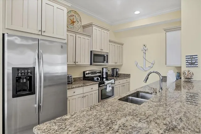 a kitchen with stainless steel appliances granite countertop a refrigerator a stove a sink and a microwave