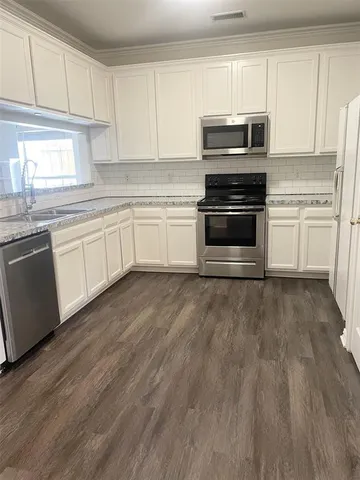 a kitchen with granite countertop white cabinets and appliances