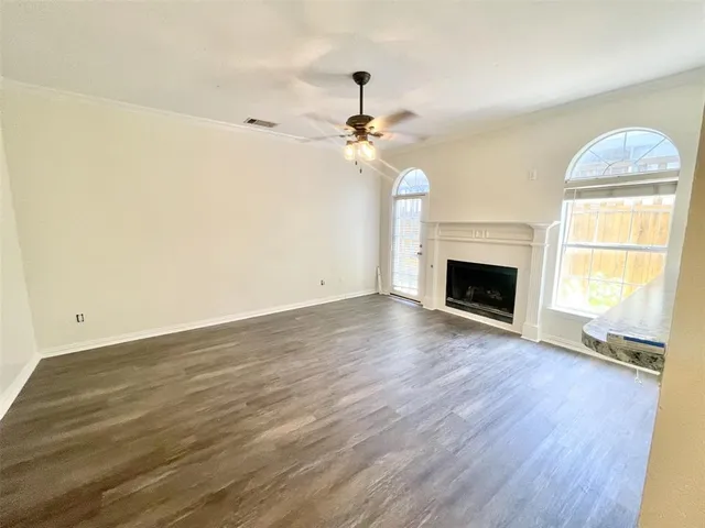an empty room with wooden floor fireplace and window
