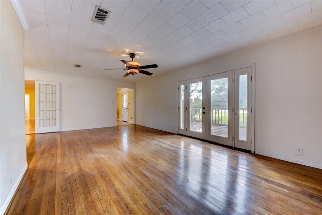 a view of an empty room with a window and wooden floor