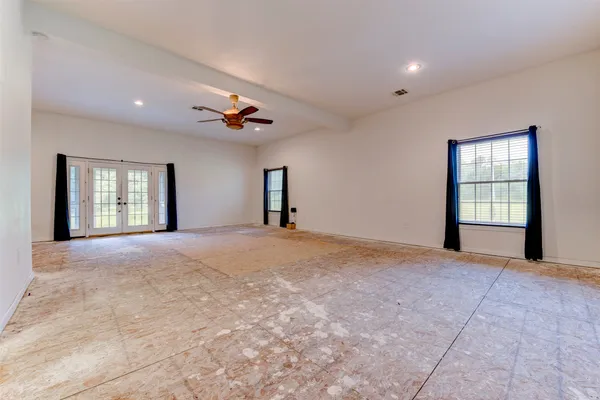 a view of empty room with windows and ceiling fan