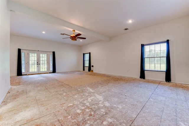 a view of empty room with windows and ceiling fan