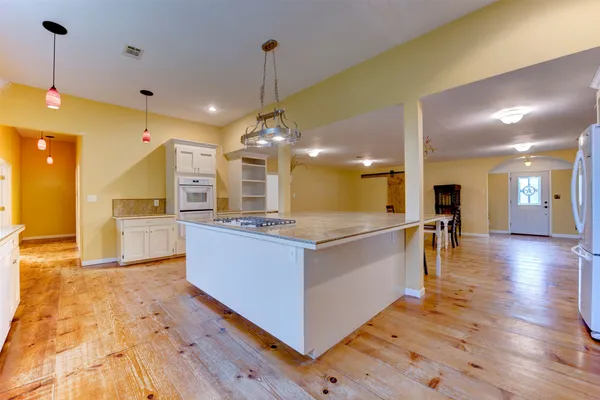 a large white kitchen with a large island oven a sink and stainless steel appliances