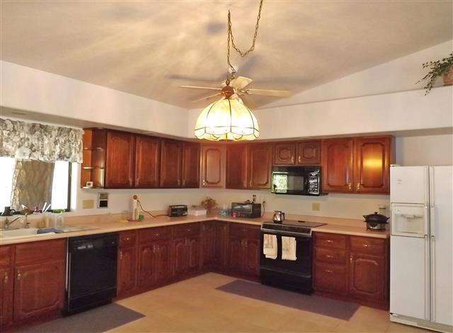 2097 Chevelon Road Overgaard, AZ 85933 - Photo 20 of 35 a kitchen with granite countertop wooden cabinets a refrigerator a sink a stove a dining table and chairs