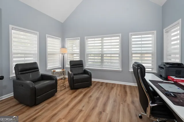 a living room with furniture hard wood floor and a floor to ceiling window
