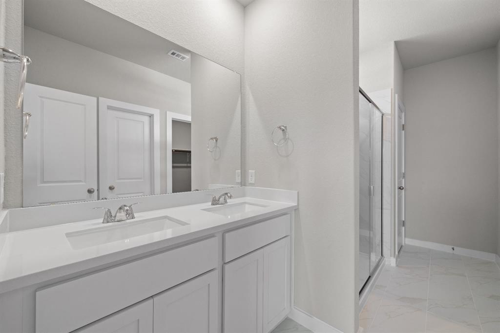 177 Sleep Hollow Jarrell, TX 76537 - Photo 16 of 24 Dual vanity with white cabinetry and integrated sinks set within a large wall-mounted mirror