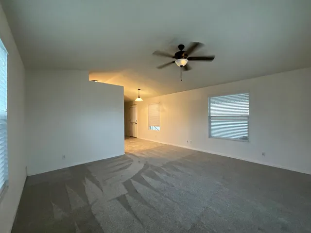 an empty room with a window and a ceiling fan