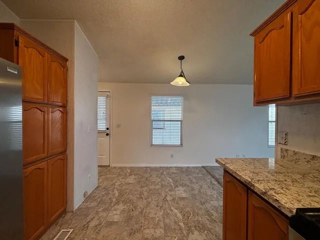 a kitchen with granite countertop a refrigerator and cabinets
