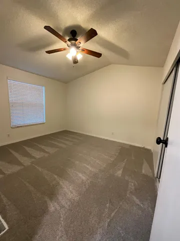 en empty room with windows and ceiling fan