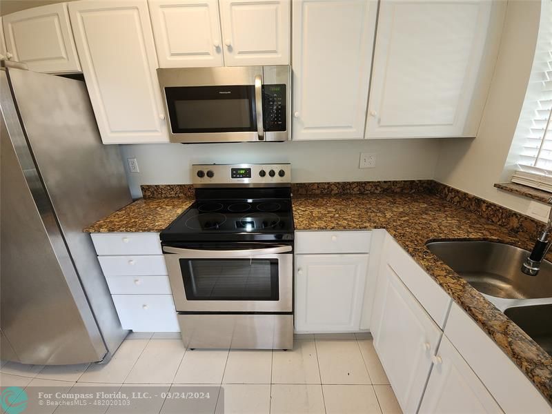 a kitchen with granite countertop a sink and a stove top oven
