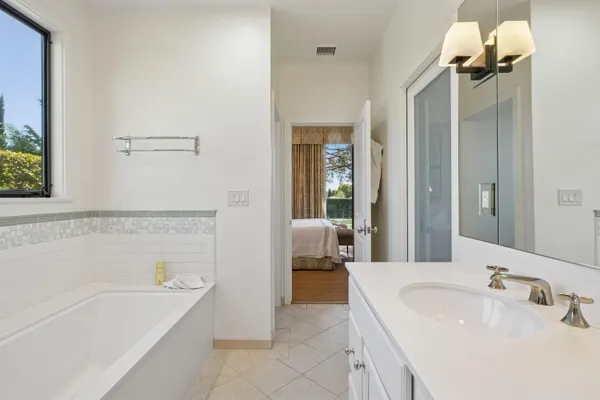 a bathroom with a tub a sink and mirror