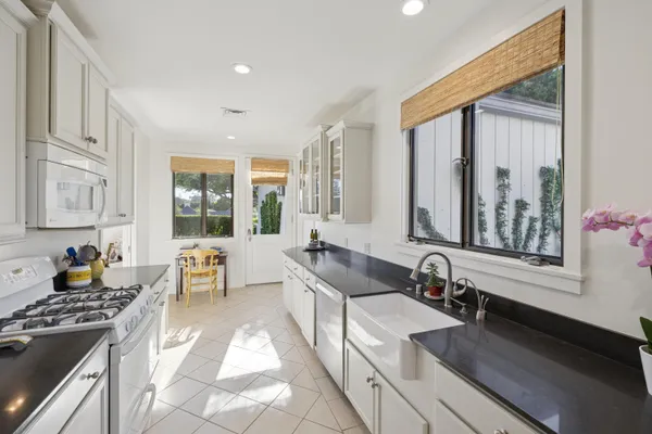 a large white kitchen with granite countertop a stove a sink and a refrigerator