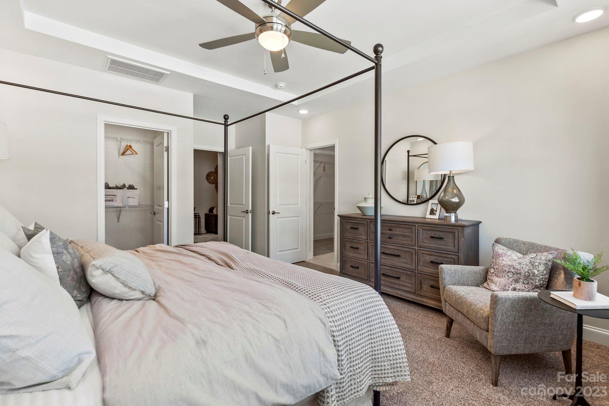 8958 Morning Mist Road Harrisburg, NC 28215 - Photo 21 of 28 a spacious bedroom with a bed a chandelier and a mirror