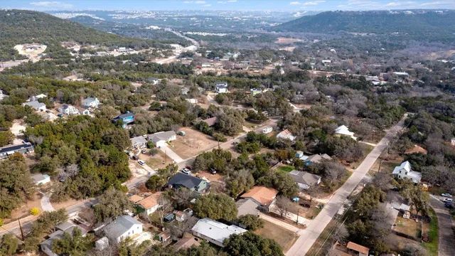 an aerial view of residential house with parking and trees