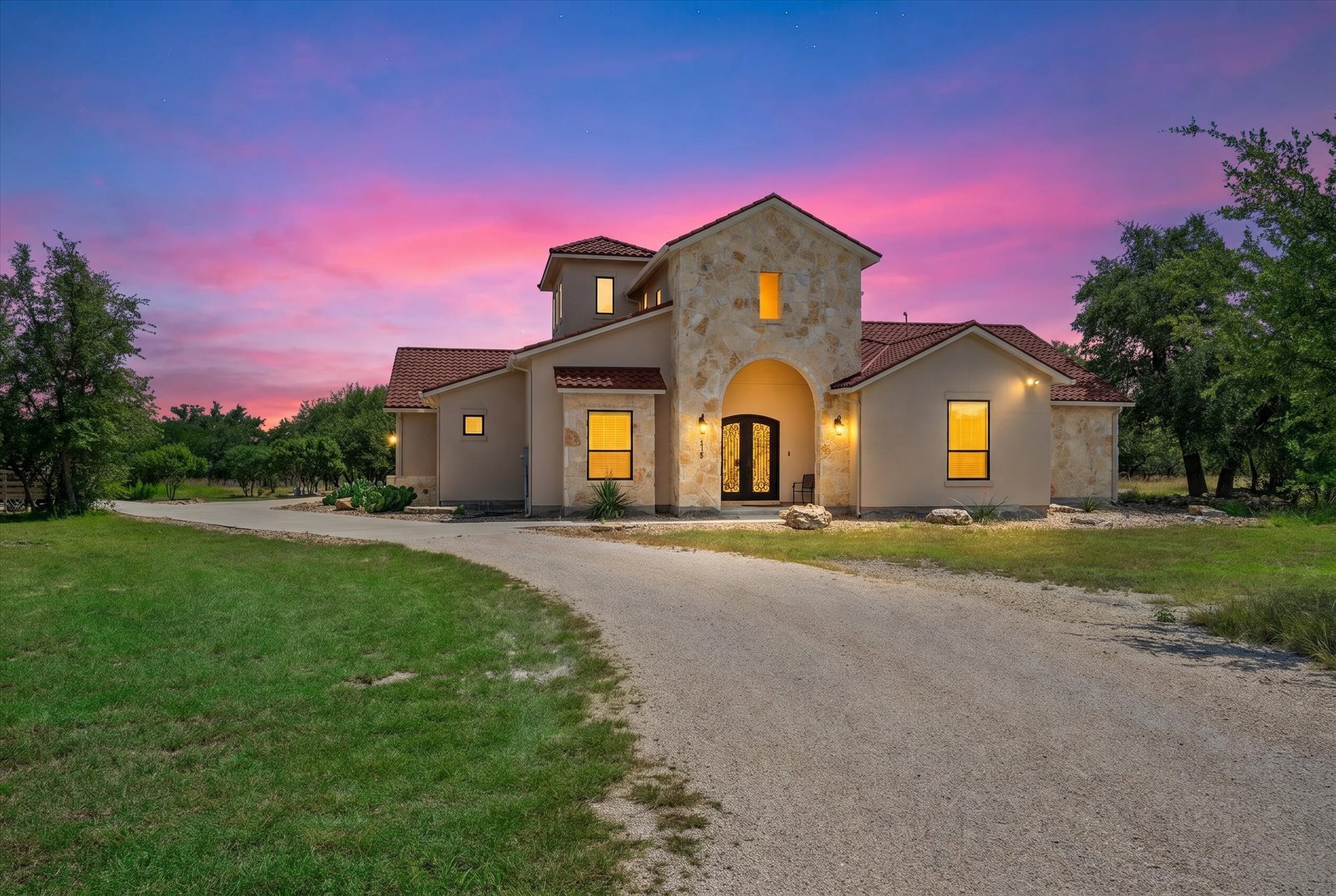 638 Strada Luca Florence, TX 76527 - Photo 2 of 38 Dramatic sunset hues illuminate the stately stucco and stone facade, welcoming guests with an arched entryway.