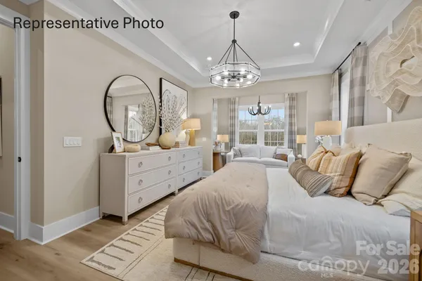 a spacious bedroom with a bed a chandelier and dresser