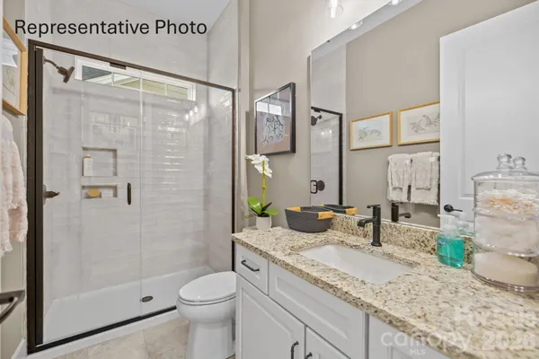 a bathroom with a granite countertop sink mirror vanity and toilet