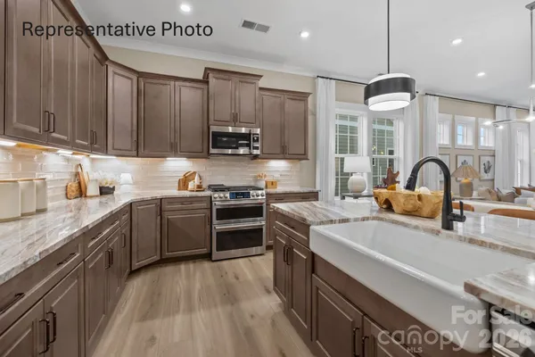 a kitchen with stainless steel appliances a sink a stove top oven a refrigerator cabinets and wooden floor