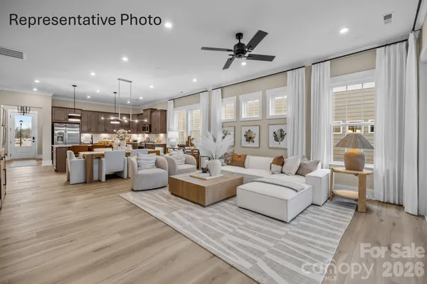 a living room with furniture kitchen view and a large window
