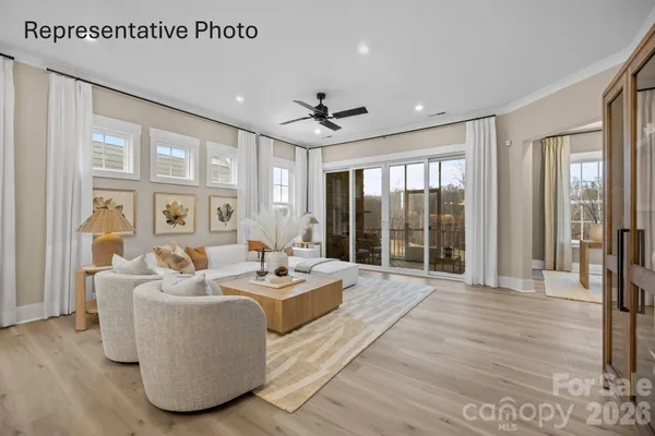 a living room with furniture large windows and wooden floor