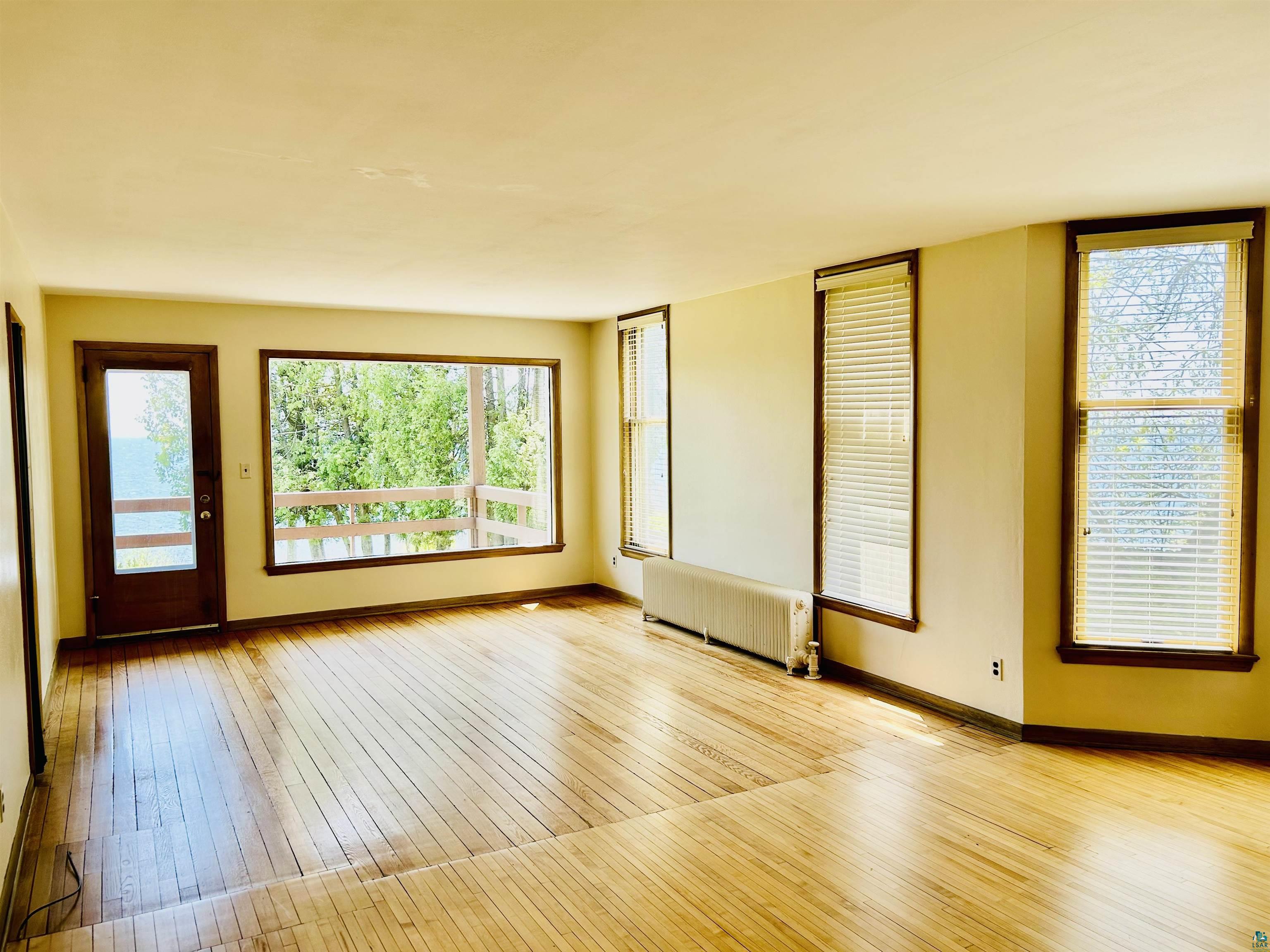 5090 London Road, Unit 1 Duluth, MN 55804 - Photo 13 of 54 Spacious interior featuring wood-finish flooring, multiple windows, a full-light door, and a built-in radiator