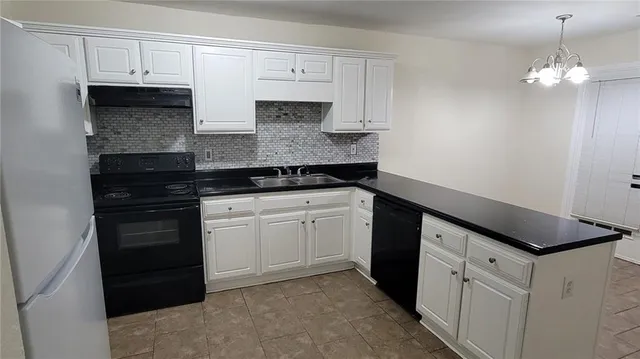 a kitchen with white cabinets and black appliances