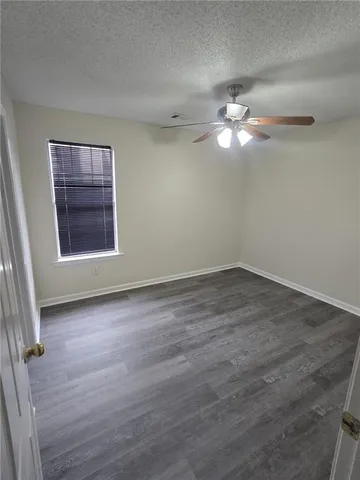 an empty room with a window and ceiling fan