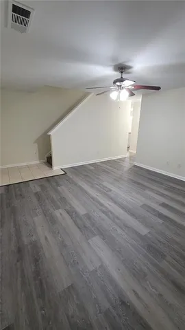 an empty room with wooden floor chandelier fan and windows