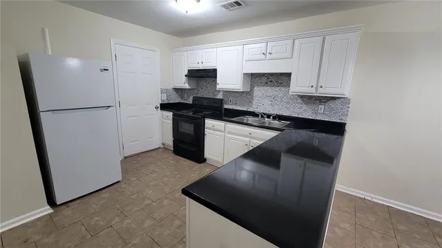 a kitchen with stainless steel appliances granite countertop a refrigerator a stove a sink and white cabinets