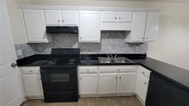 a kitchen with white cabinets and black appliances